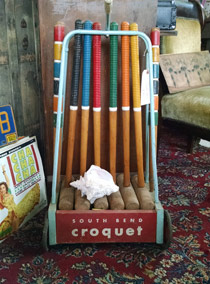 A rack of wooden croquet sticks in front of a book.