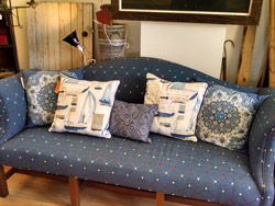 A blue couch with several pillows on it.